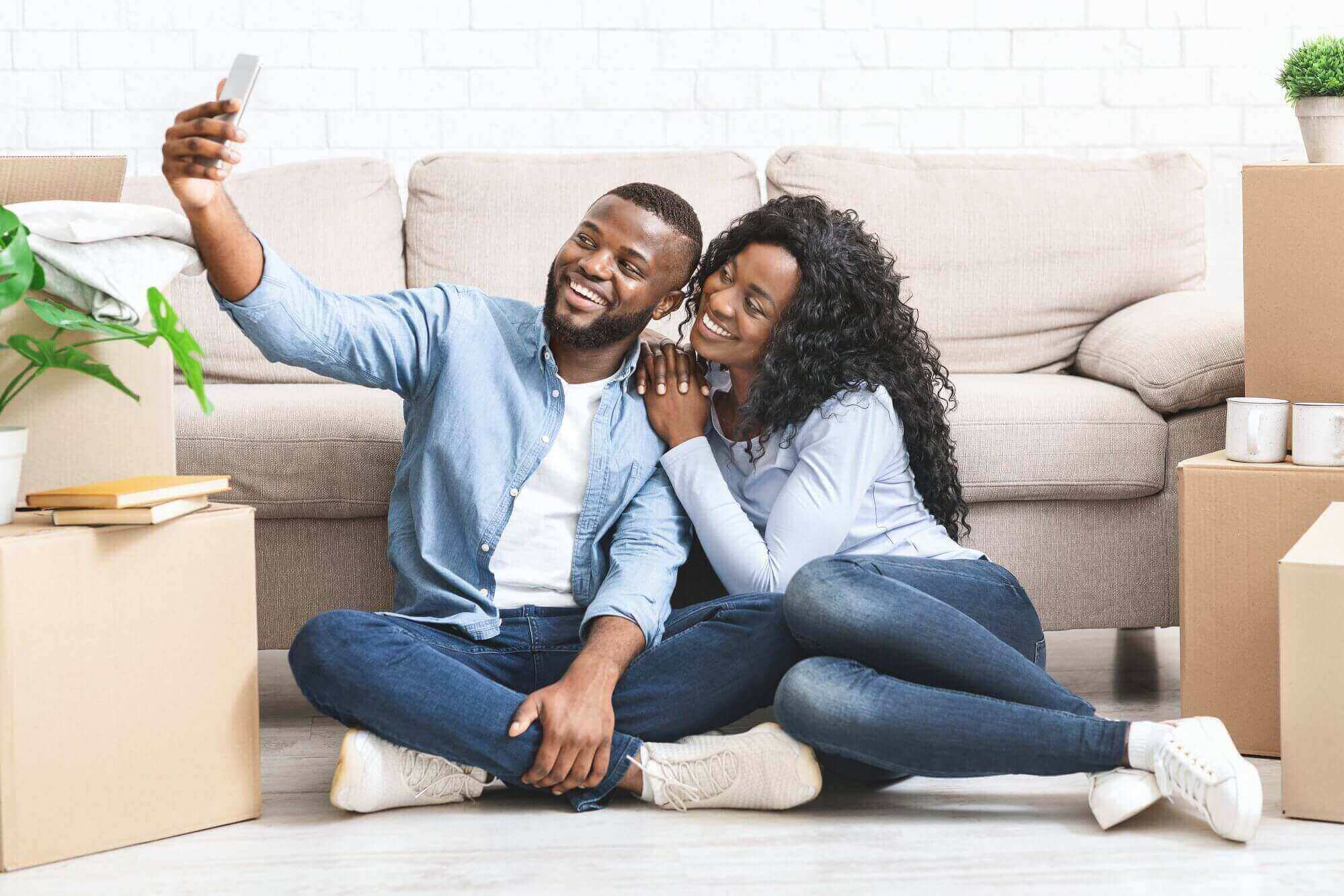 Happy couple moving in new apartment, taking selfie on phone