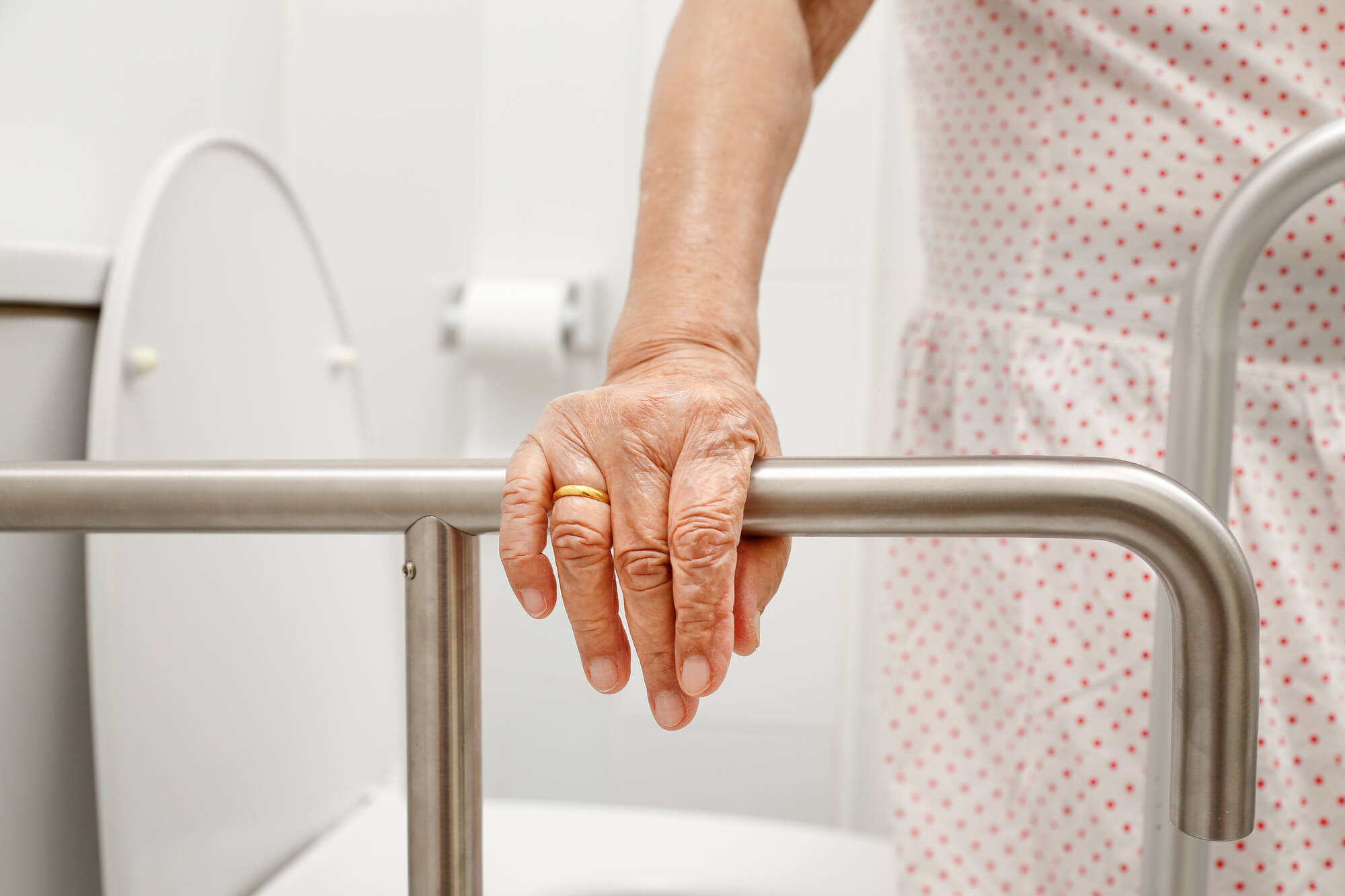 Elderly woman holding on handrail in toilet